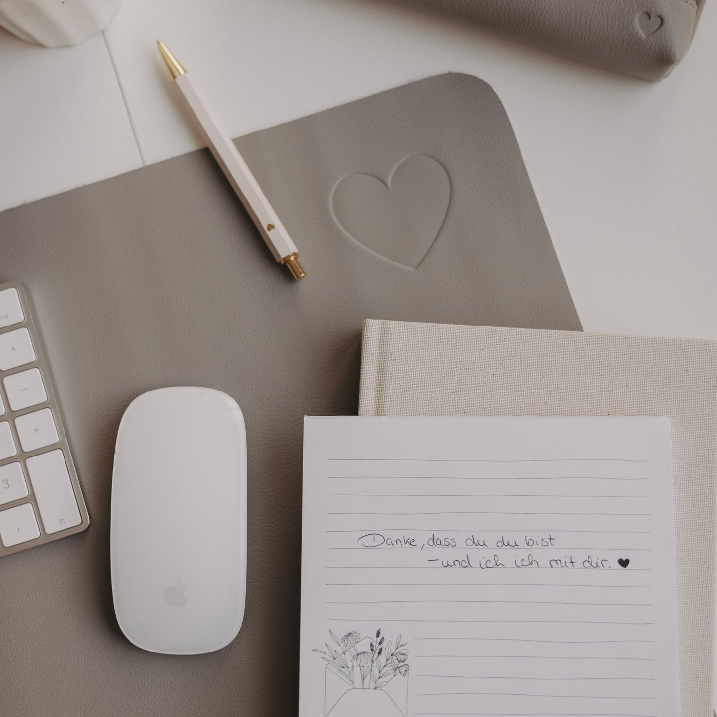 Detail graue Schreibtischunterlage mit Herz-Prägung, Maus und Stift im minimalistischen Design