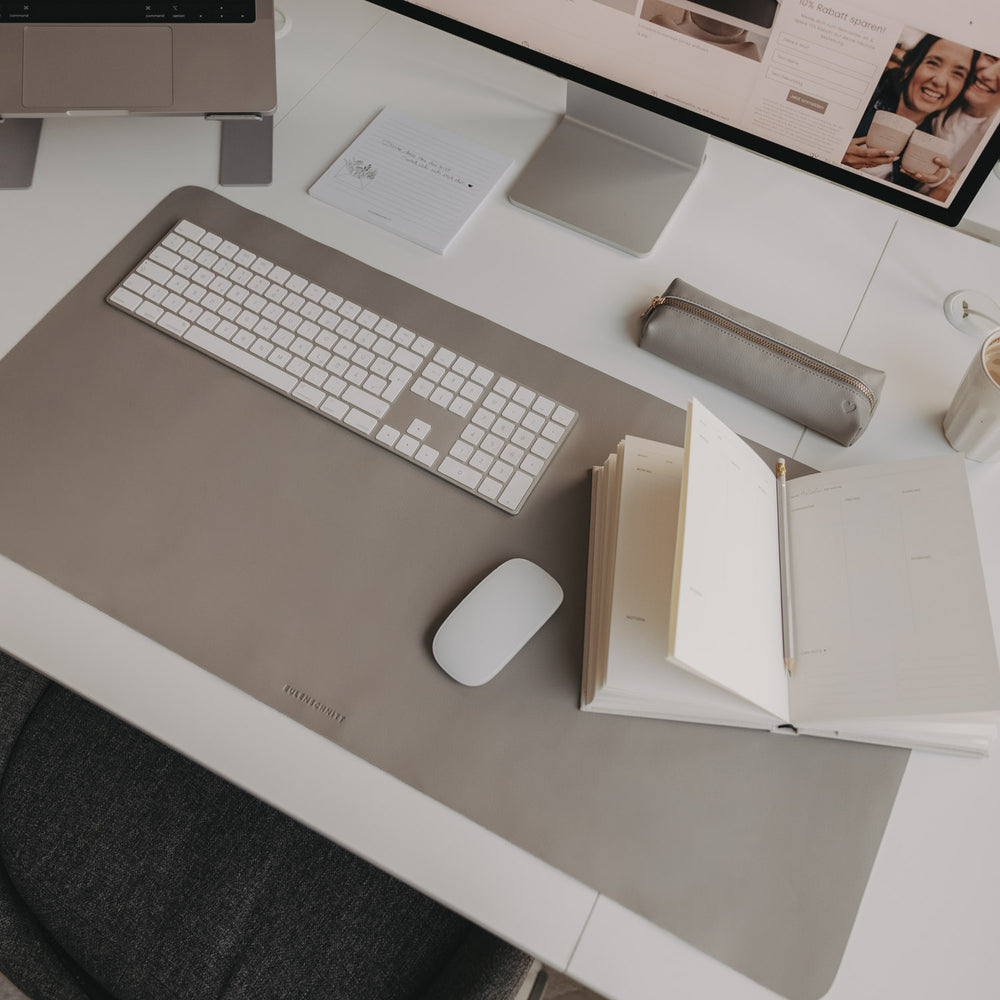 Arbeitsplatz mit grauer Schreibtischunterlage Herz, Laptop, Monitor und Notizbuch minimalistisch