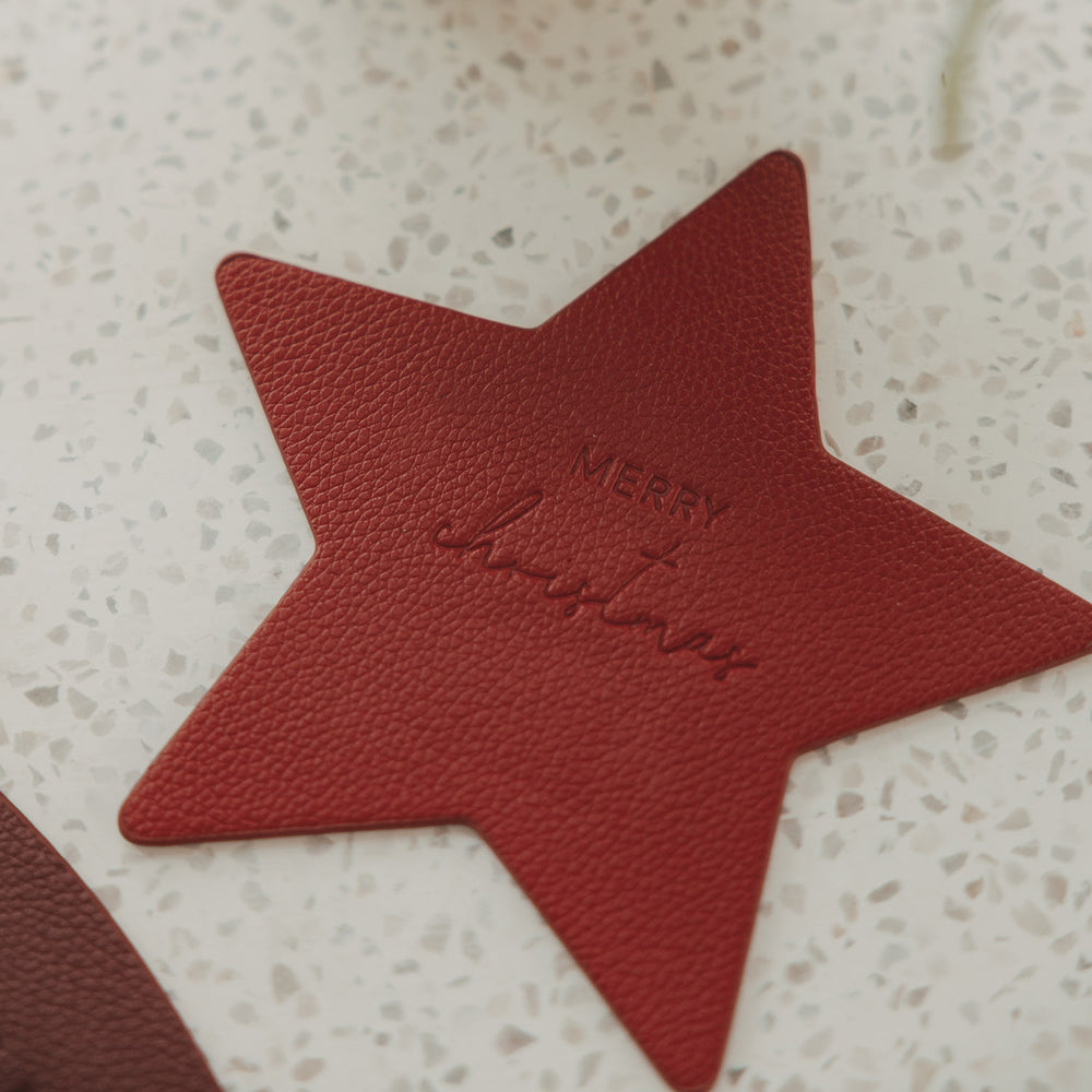 Roter sternförmiger Untersetzer in Lederoptik mit geprägtem Schriftzug „Merry Christmas“