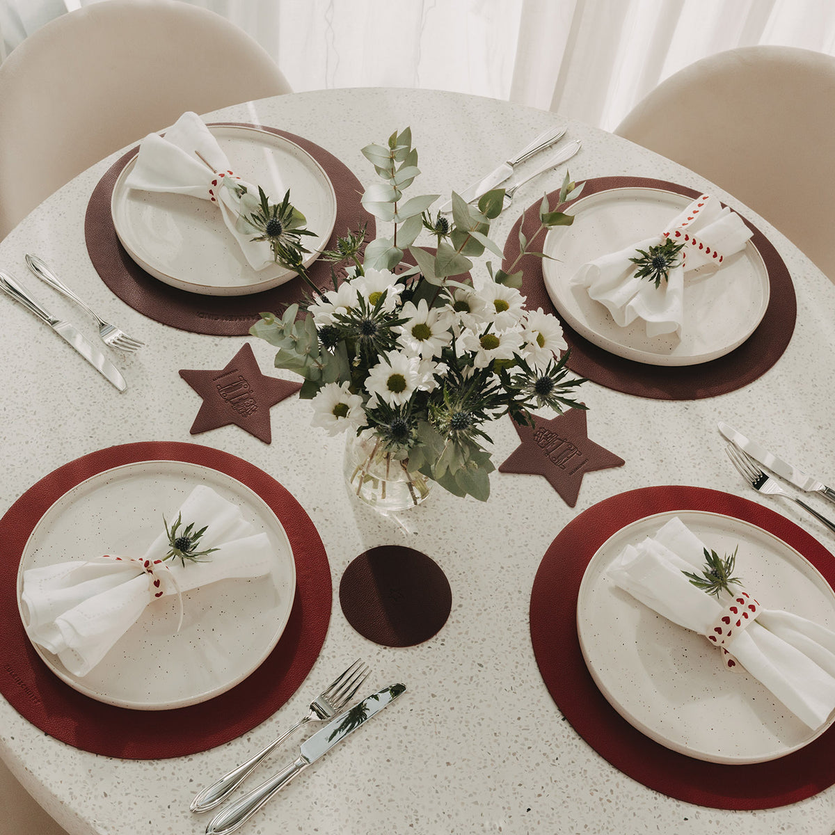Weihnachtlich gedeckter Tisch mit roten Platzsets und sternförmigen Untersetzern