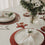 Festlich gedeckter Tisch mit roten Platzsets, Stern-Untersetzer, Gläsern und Blumen