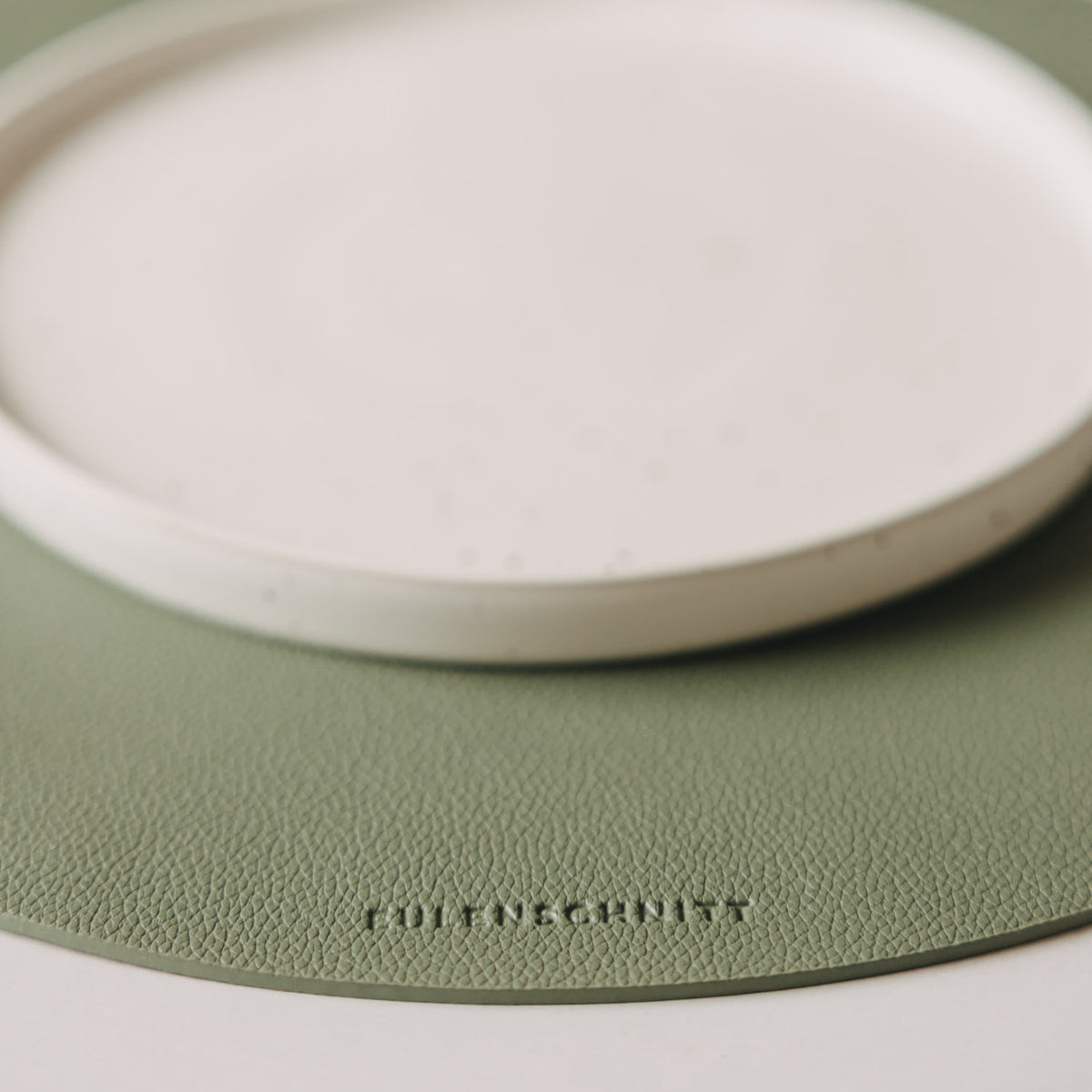 Detailaufnahme des salbeigrünen Platzsets in Lederoptik mit Eulenschnitt-Logo
