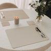 Gedeckter Tisch mit cremefarbenen Platzsets und quadratischen Untersetzern, Kerze und Blumenstrauß