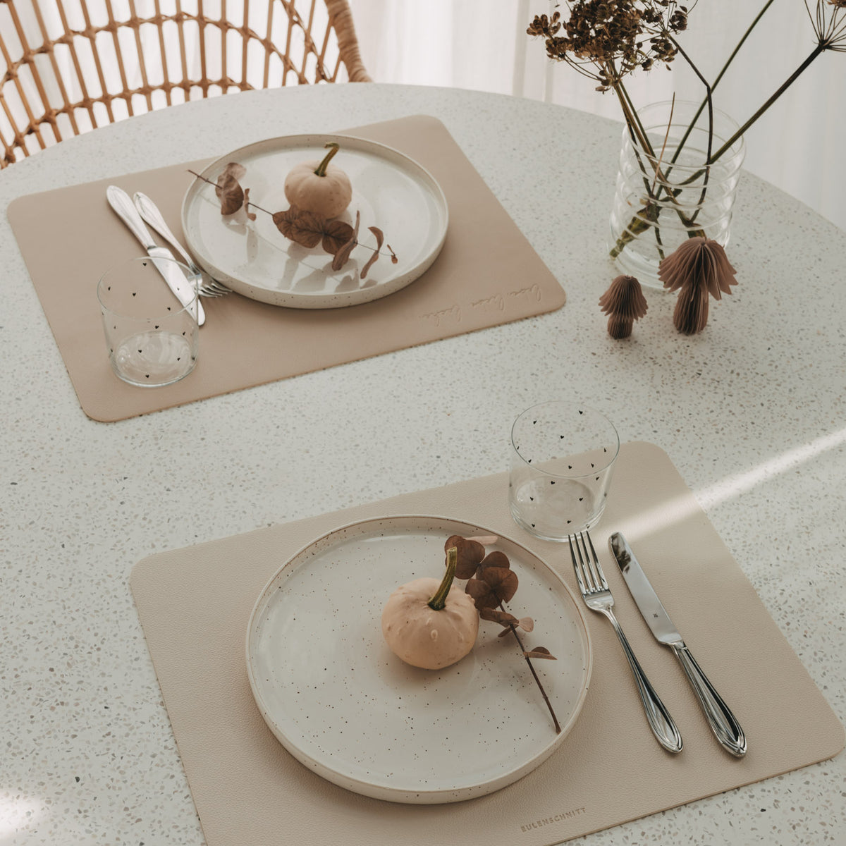 Zwei wendbare Platzsets in Creme und Beige mit Tellern, Besteck und Gläsern auf Esstisch