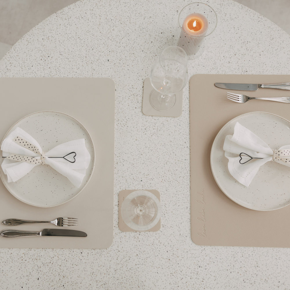 Zwei wendbare Platzsets in Creme und Beige mit gedeckten Tellern und Herz-Serviettenhaltern