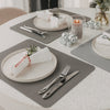 Graue wendbare Platzsets auf gedecktem Esstisch mit Tellern, Besteck und Kerze
