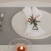 Graues Platzset mit Teller, weißer Serviette und herzförmigem Serviettenhalter