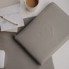 Laptop Sleeve grau mit geprägtem Herz von Eulenschnitt auf Schreibtisch mit Notizblock, Stift und Kaffee