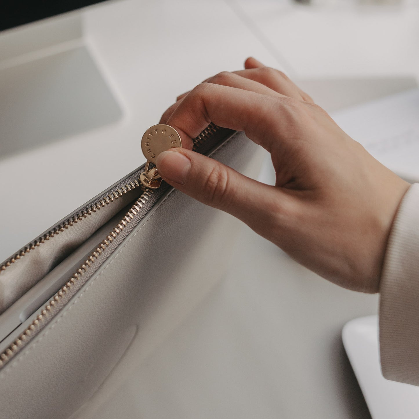 Hand öffnet graues Laptop Sleeve mit Herzprägung und goldenem Reißverschluss von Eulenschnitt