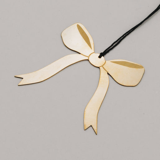 Detailaufnahme des goldenen Schleifenanhängers aus Metall mit feiner Struktur und schwarzem Band.