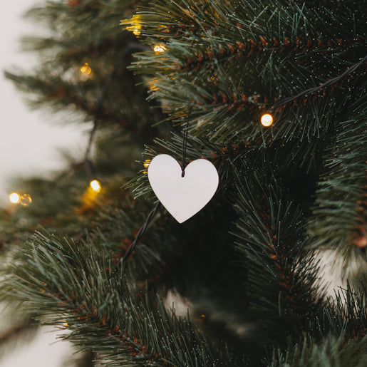 Silberner Herzanhänger am Weihnachtsbaum mit Lichterkette – festliche Dekoration 