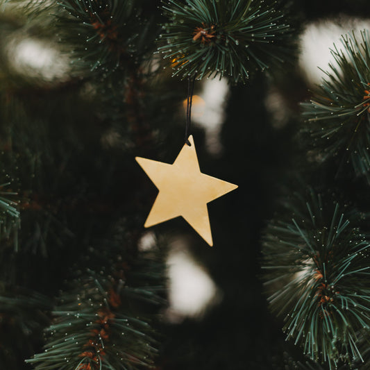 Goldener Sternanhänger am Tannenbaum mit Lichterkette – festliche Weihnachtsdeko mit elegantem Glanz.