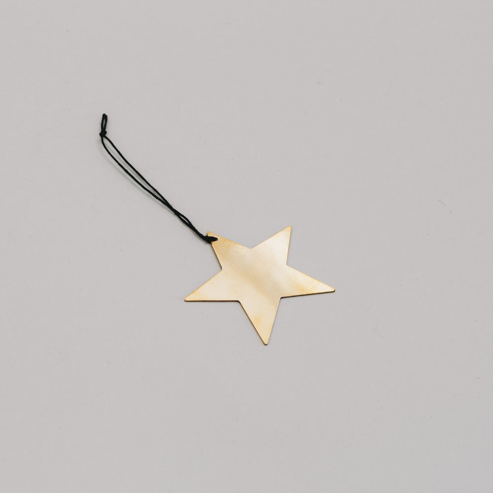 Anhänger Stern goldfarben in flacher Perspektive – filigrane Weihnachtsdeko aus Metall mit schwarzem Band.