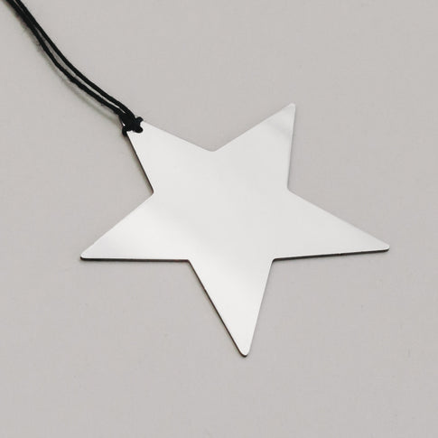 Detailaufnahme des silbernen Metallsterns mit schwarzer Schnur, zeigt reflektierende Oberfläche.