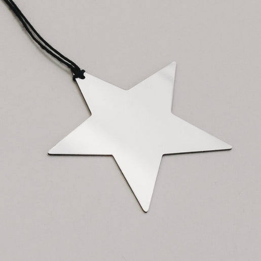 Detailaufnahme des silbernen Metallsterns mit schwarzer Schnur, zeigt reflektierende Oberfläche.