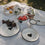 Emaille-Geschirr mit schwarzem Herz im sommerlichen Picknick-Setting auf einer hellen Decke.
