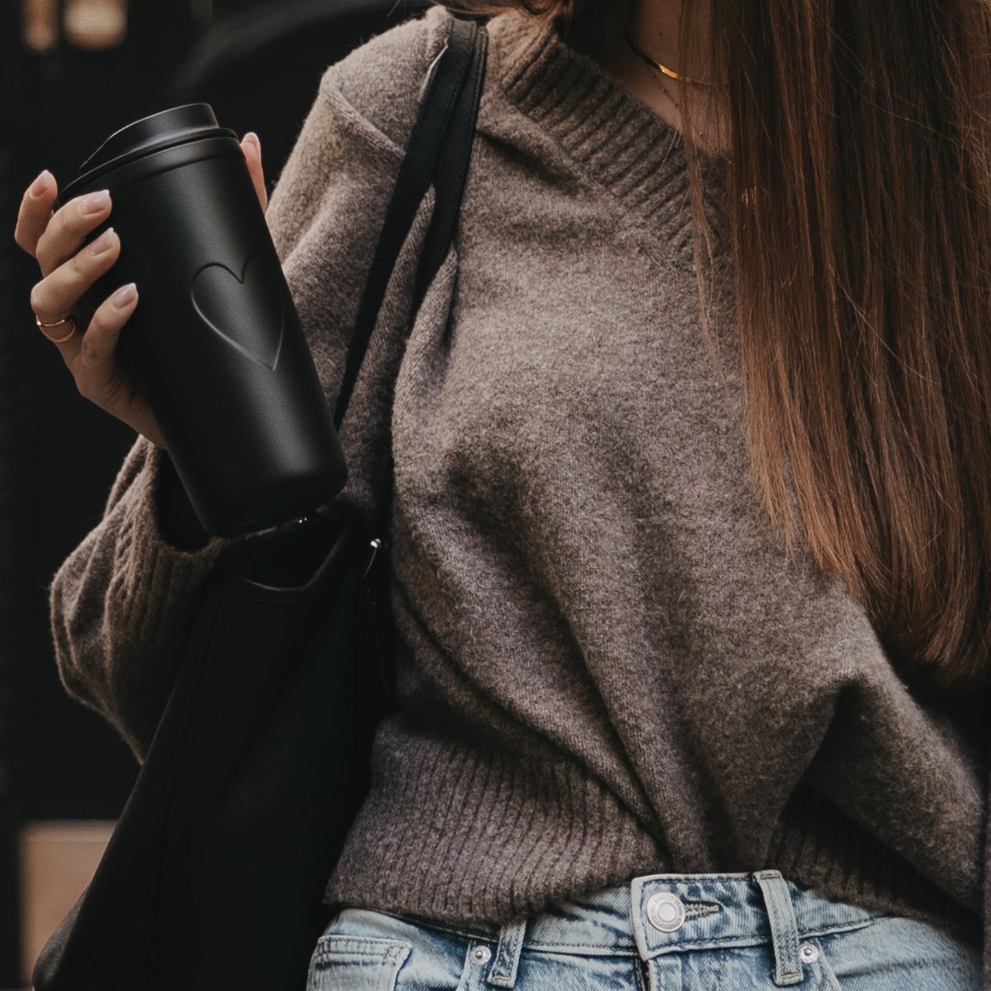 Frau hält To-go Becher Herz schwarz in der Hand mit Handtsche, eleganter Begleiter für unterwegs.