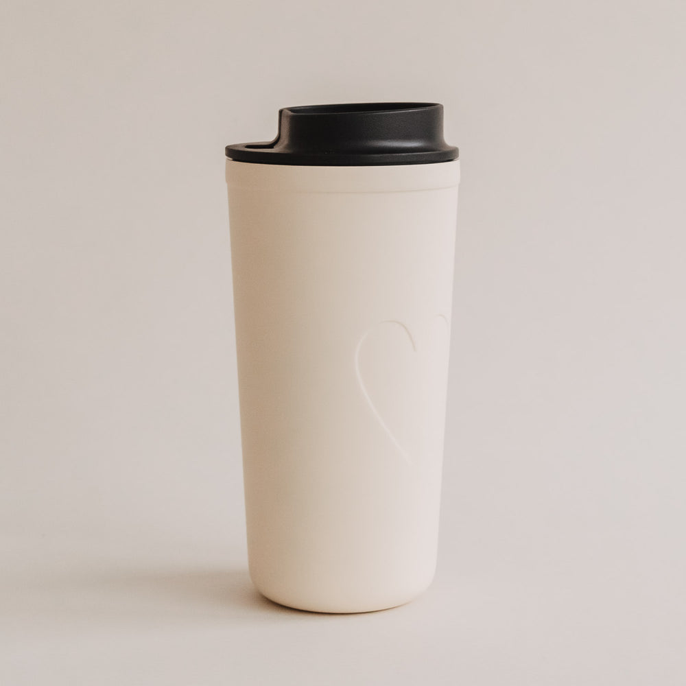 Freigestellter To-go Becher Herz creme mit schwarzem Deckel, schlichtes Design.
