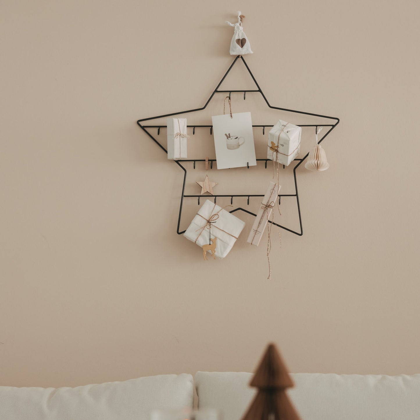 Kleiner Adventskalender Stern aus Metall an der Wand, minimalistisch mit Geschenken und Anhängern dekoriert