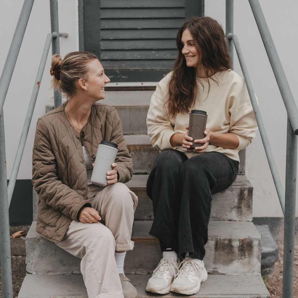 Zwei Frauen mit braunem und beigem To-go-Thermobecher mit Herzmotiv