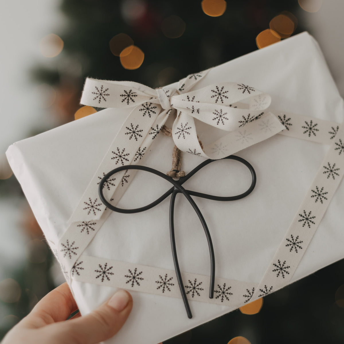 Anthrazitfarbener Metallanhänger Schleife als Geschenkanhänger an einem weihnachtlich verpackten Geschenk.