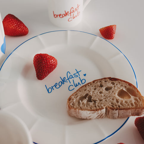 Frühstücksteller „breakfast club“ mit hellblauem Rand im Detail – liebevoll arrangiert mit Erdbeere und Brot