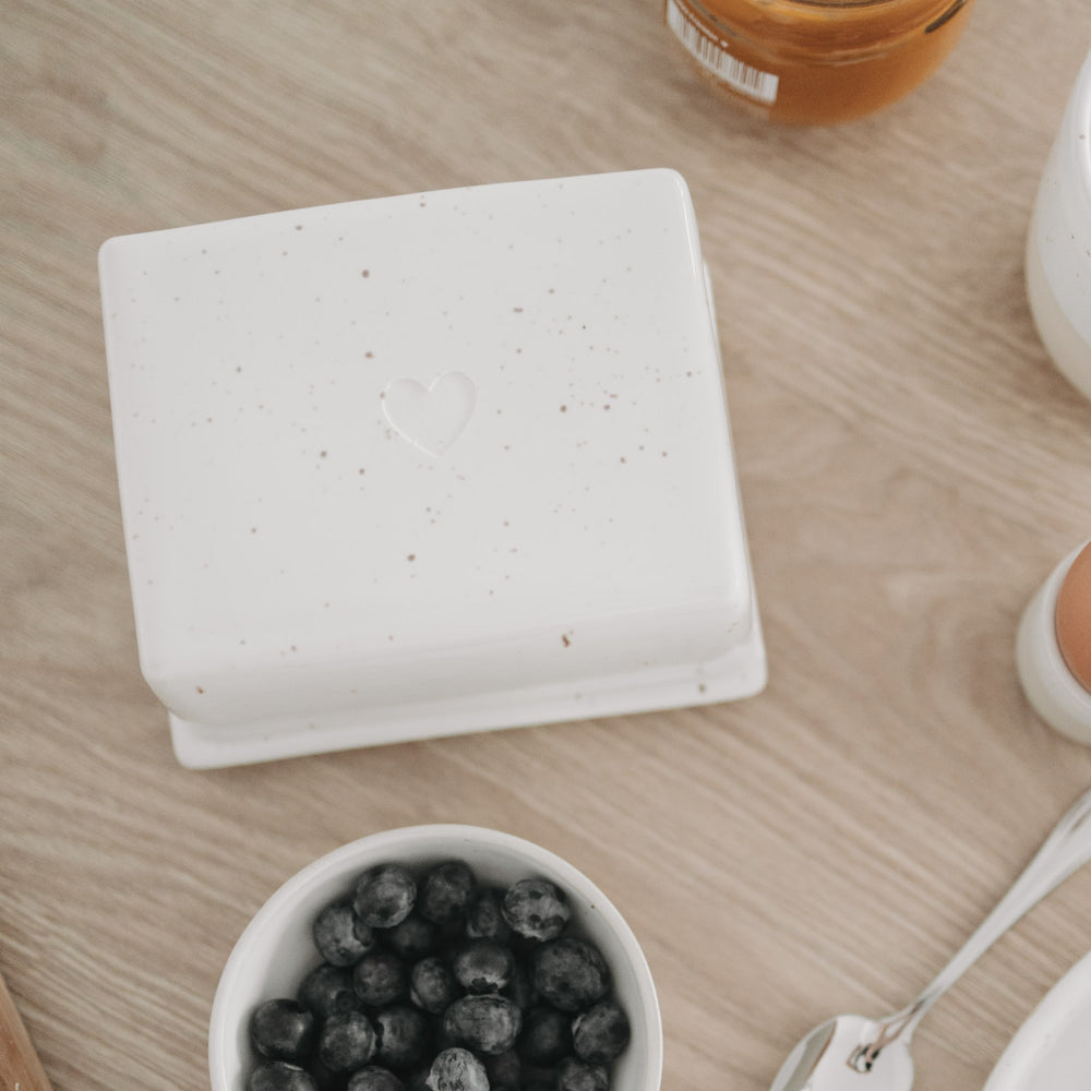 Butterdose mit Herz-Prägung aus Keramik, stilvoll inszeniert auf hellem Holztisch
