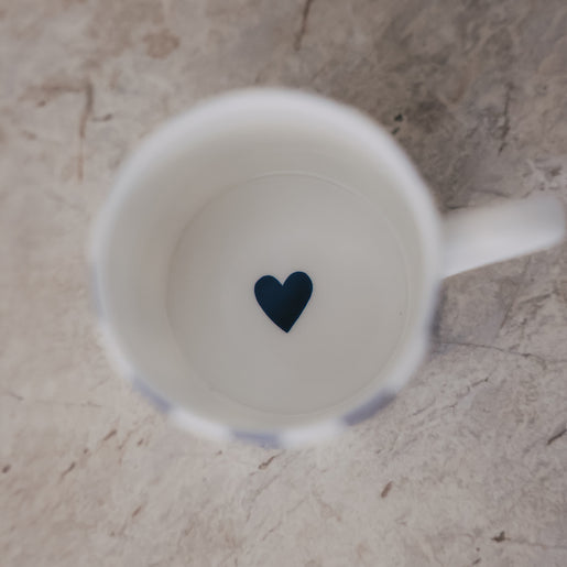 Blick in eine Tasse mit schlichtem weißem Inneren und kleinem dunkelblauen Herz am Boden.