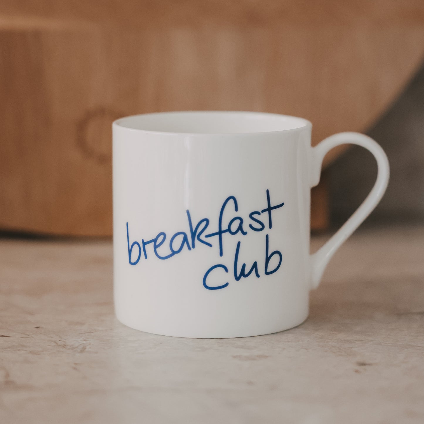 Weiße Tasse mit handgeschriebenem Schriftzug „breakfast club“ in Dunkelblau