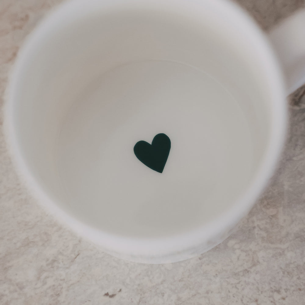 Innenansicht einer weißen Tasse mit kleinem grünem Herz am Boden