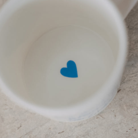 Draufsicht in eine weiße Tasse mit kleinem blauem Herz auf dem Tassenboden