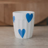Weißer Keramikbecher mit großen blauen Herzmotiven, schlichtes modernes Design