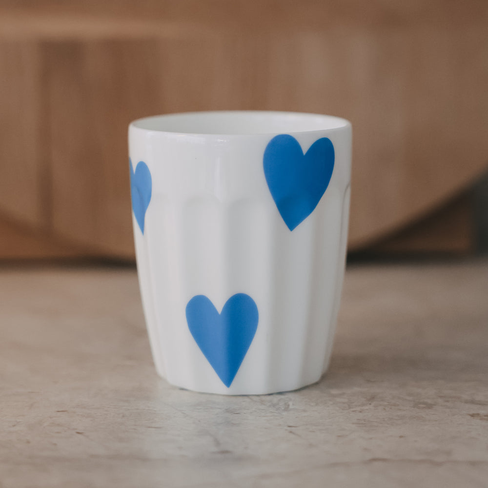 Weißer Keramikbecher mit großen blauen Herzmotiven, schlichtes modernes Design