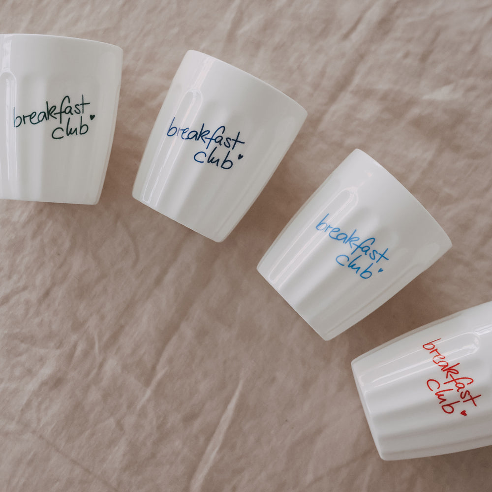 Keramikbecher „breakfast club“ dekorativ auf hellem Untergrund arrangiert