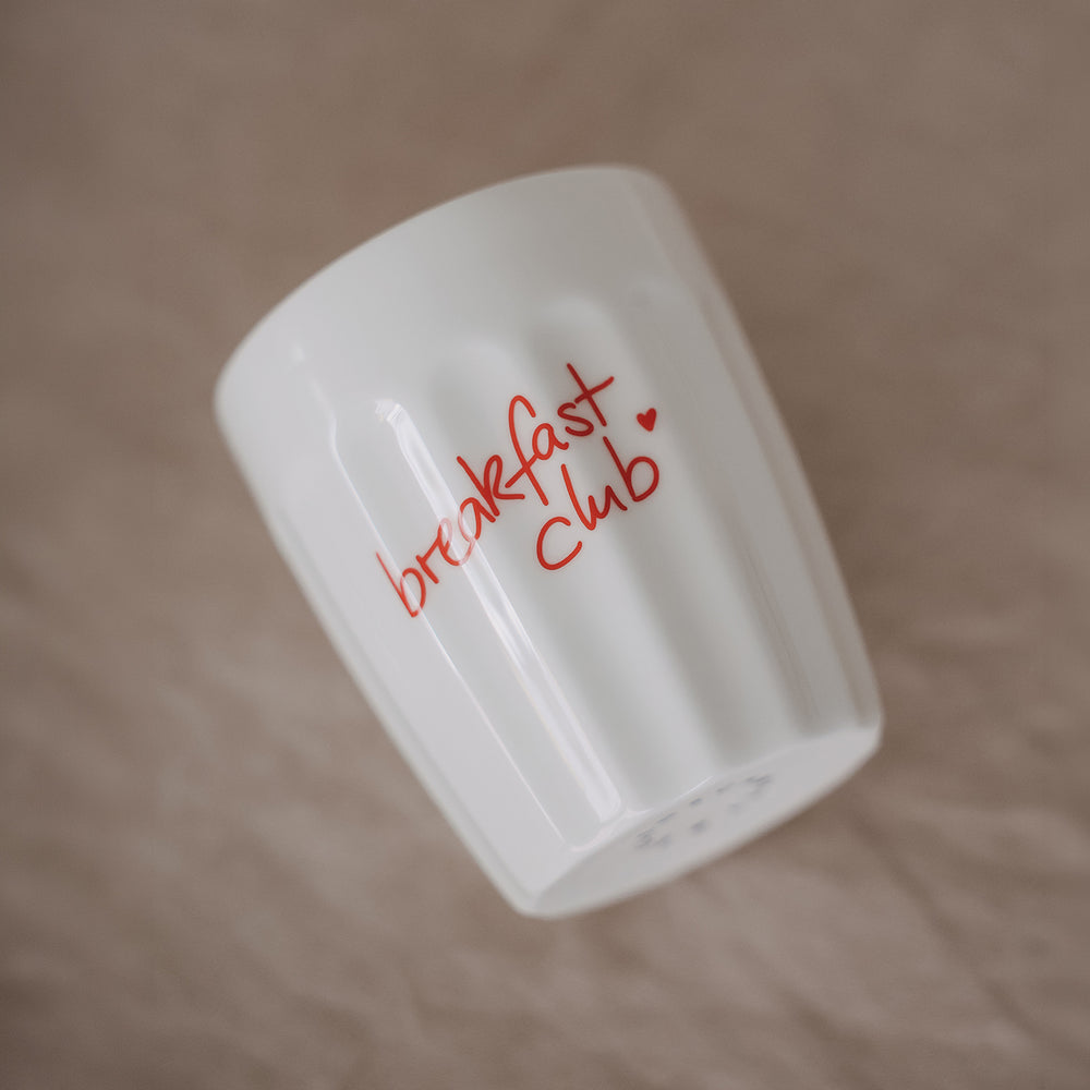 Weißer Keramikbecher „breakfast club“ mit rotem Schriftzug im Frühstücks-Setting mit Erdbeeren