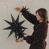 Großer schwarzer Papierstern mit Aufhängung und Lichterkette als moderne Weihnachtsdekoration