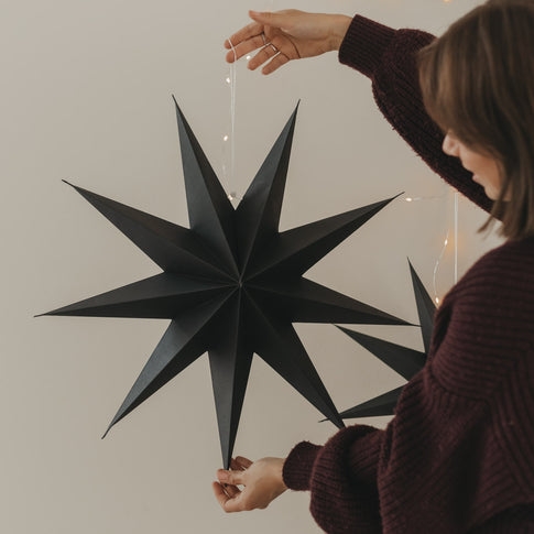 Schwarzer Papierstern mit langen Spitzen und Aufhängung als stilvolle Weihnachtsdekoration
