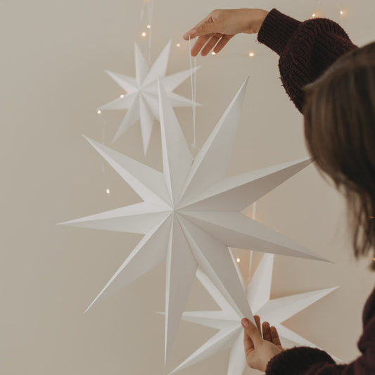 Großer weißer Papierstern mit langen Spitzen und Aufhängung als stilvolle Weihnachtsdekoration