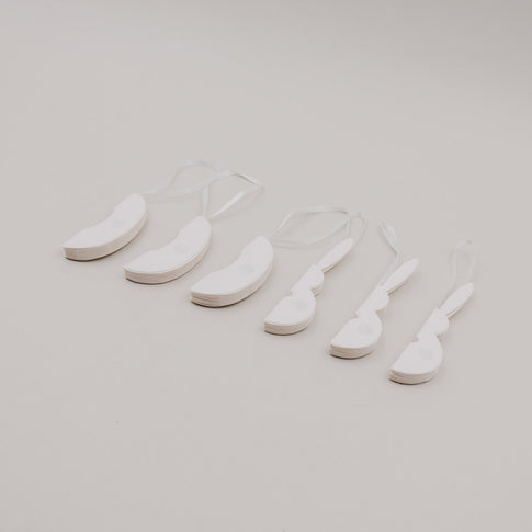 Flach gefaltete beige Papieranhänger in Ei- und Hasenform mit Bändern.