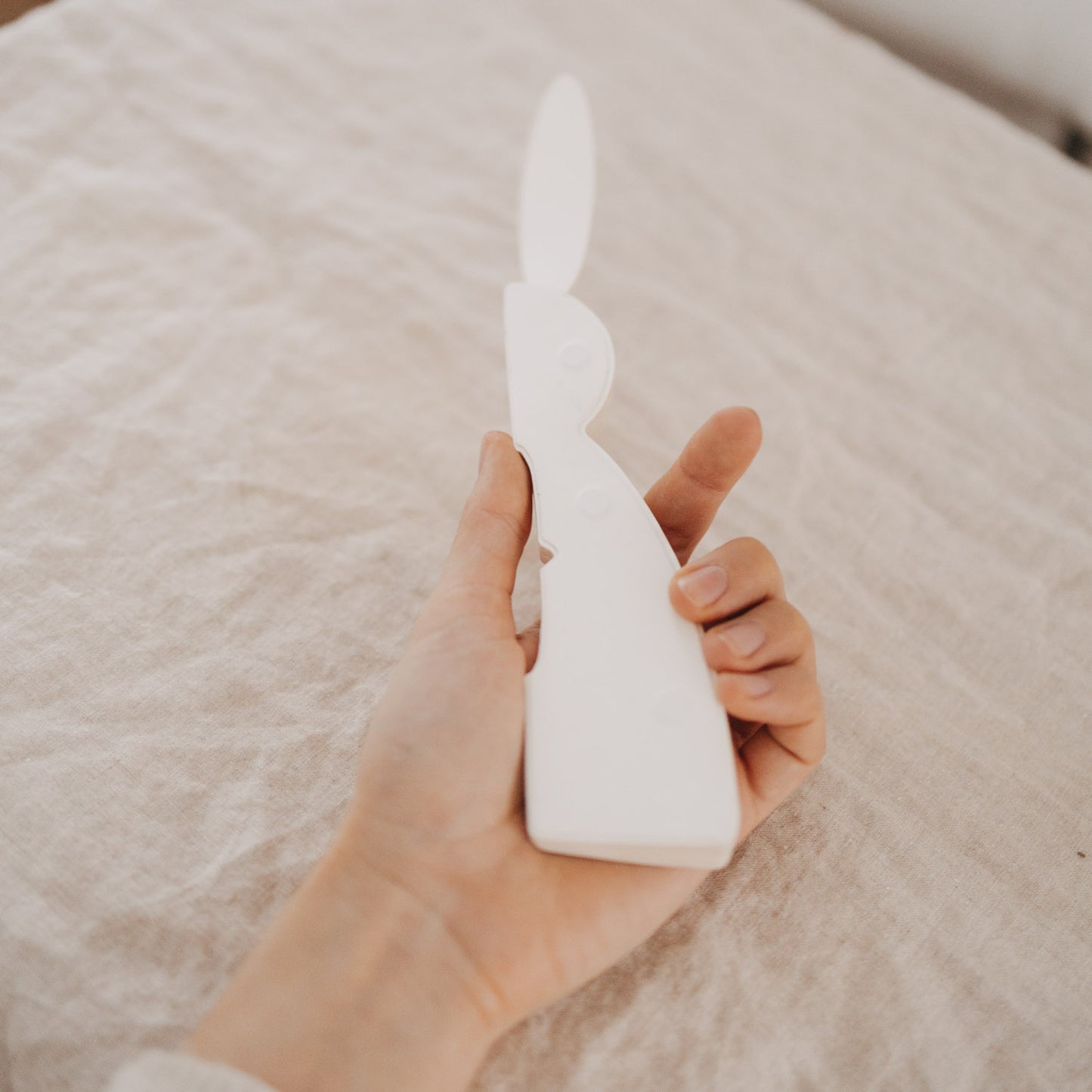 Hand hält flachen beigen Papierhasen zum Aufklappen, DIY-Osterdeko im Detail.