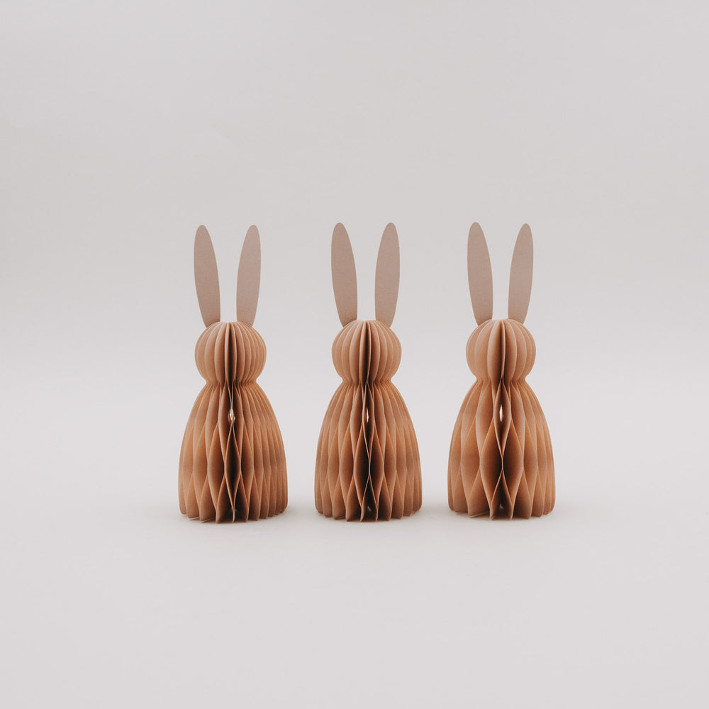 Drei peachfarbene Papierhasen im Honeycomb-Look vor hellem Hintergrund als Osterdeko.
