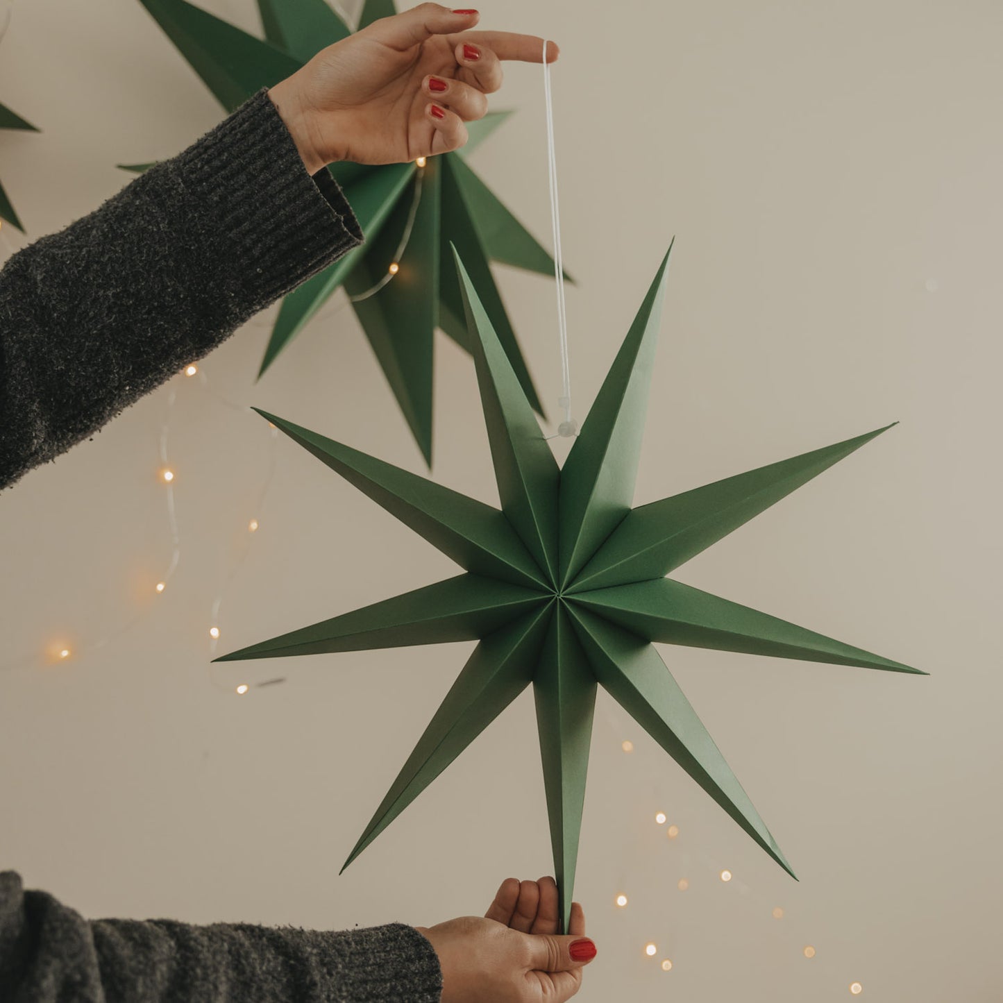 Dunkelgrüner Papierstern mit langen Spitzen und weißer Aufhängung als moderne Weihnachtsdekoration