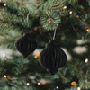 Zwei schwarze Papieranhänger in Kugelform als moderner Christbaumschmuck am Weihnachtsbaum