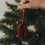 Rote Papierglocke als Christbaumschmuck wird an den Weihnachtsbaum gehängt