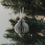 Grauer Papieranhänger in Kugelform am Weihnachtsbaum mit warmen Lichtern