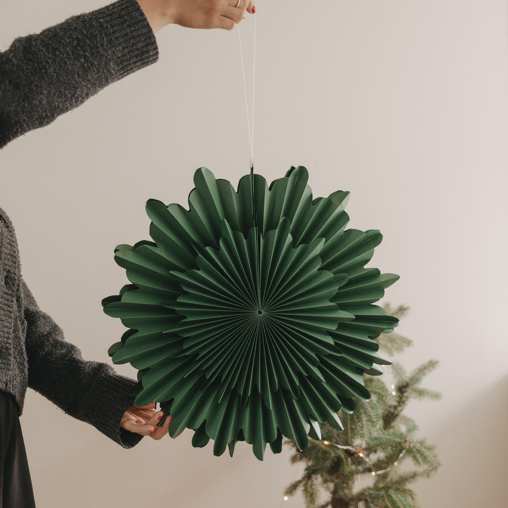 Grüne Papierschneeflocke 45 cm als hängende Weihnachtsdekoration neben Tannenbaum