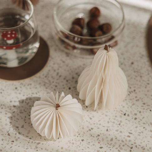 Zwei kleine weiße Papierkürbisse mit feiner Faltstruktur als minimalistische Herbstdeko