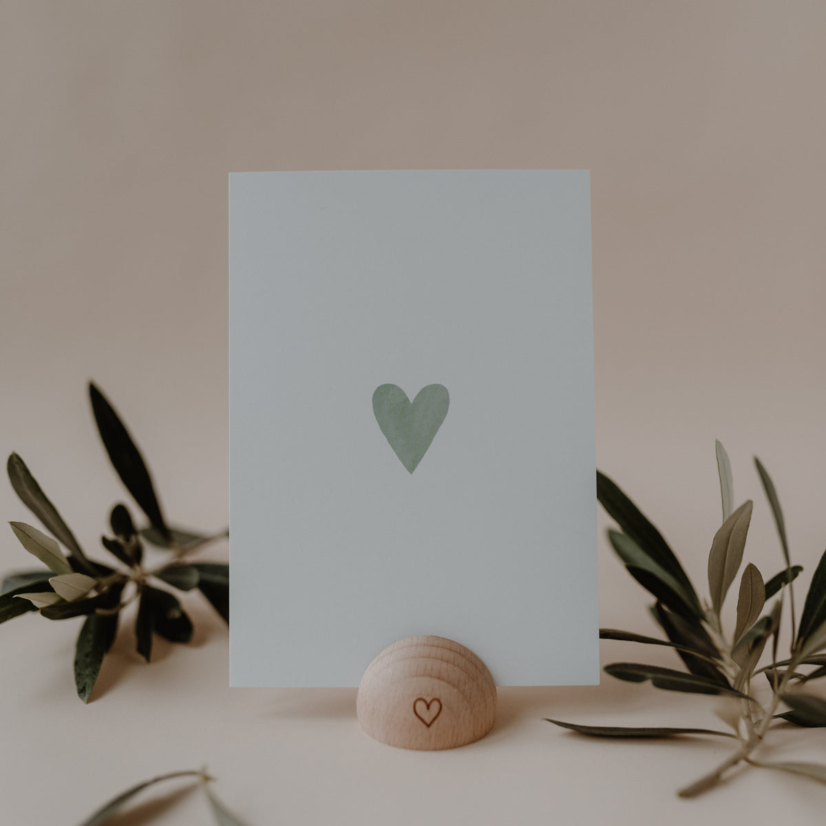Minimalistische Eulenschnitt Aquarellkarte mit mintgrünem Herz, dekoriert mit Zweigen und einem Kartenhalter aus Holz.
