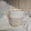 Keramikbecher „Hello New Day“ in Beige und Weiß mit Herz, gefüllt mit Kaffee