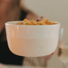 Beige Keramikschüssel mit Herz, weiß gesprenkeltem Rand und Pommes in der Hand